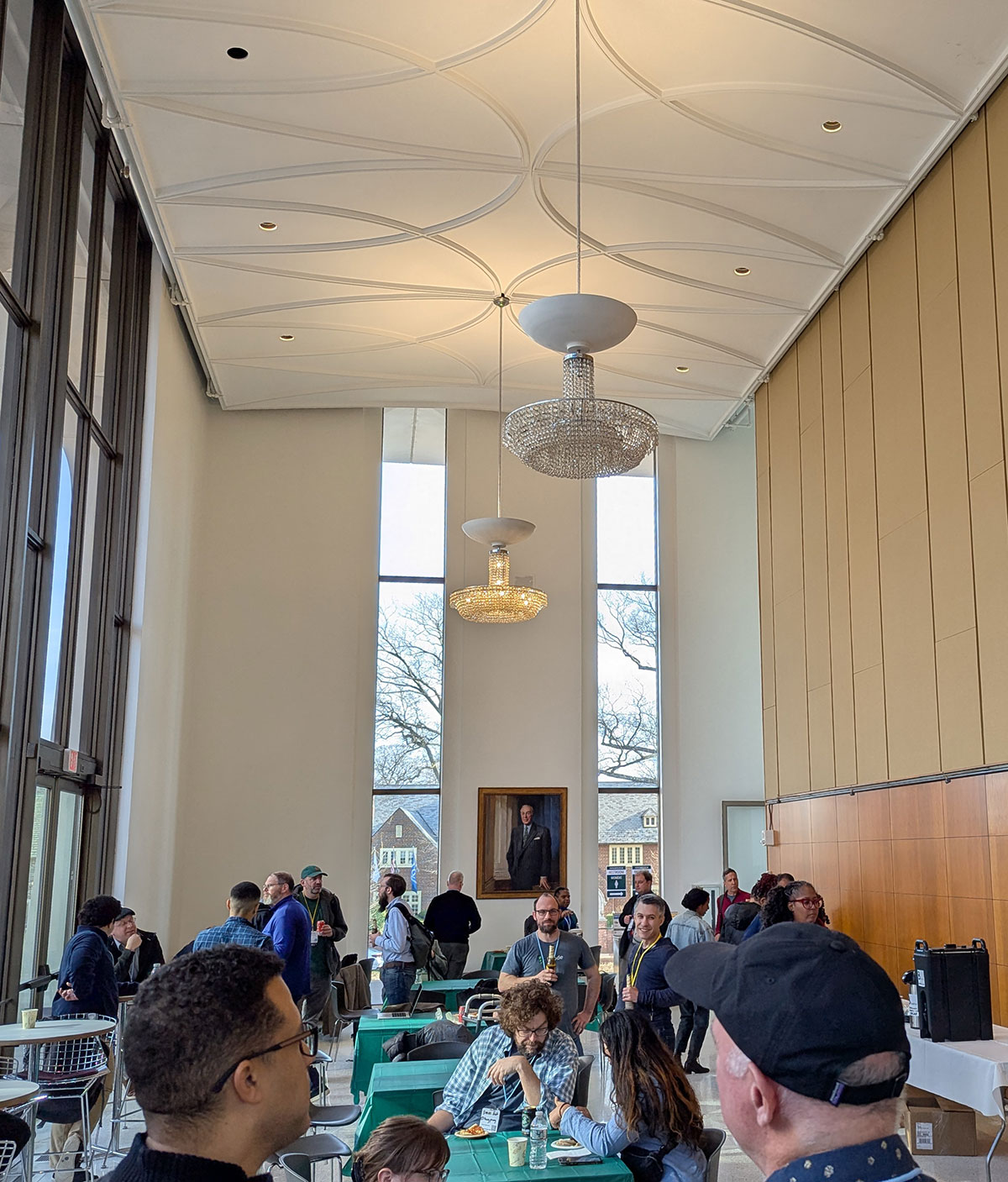 Attendees chatting during afterparty in tall room with floor to ceiling windows